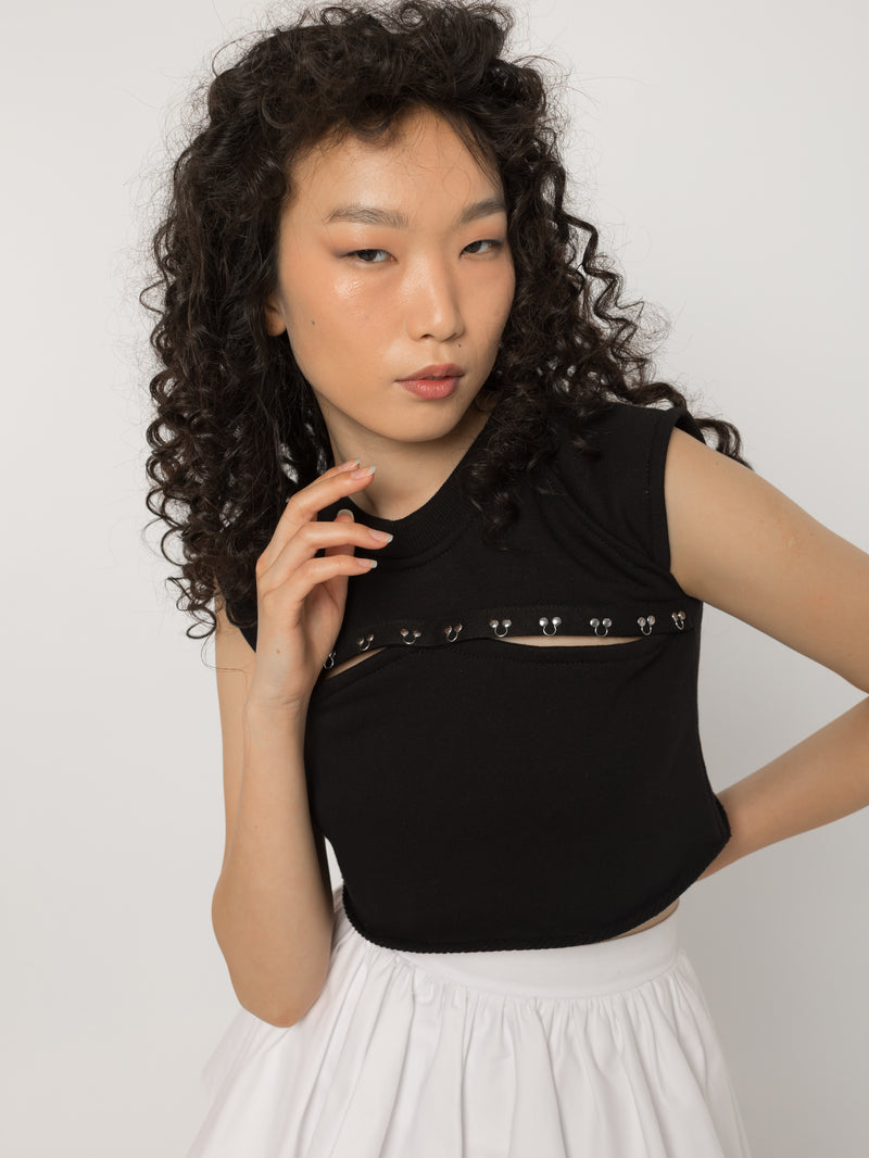 Chest cutout of the black crop top set with silver steel rings, close view