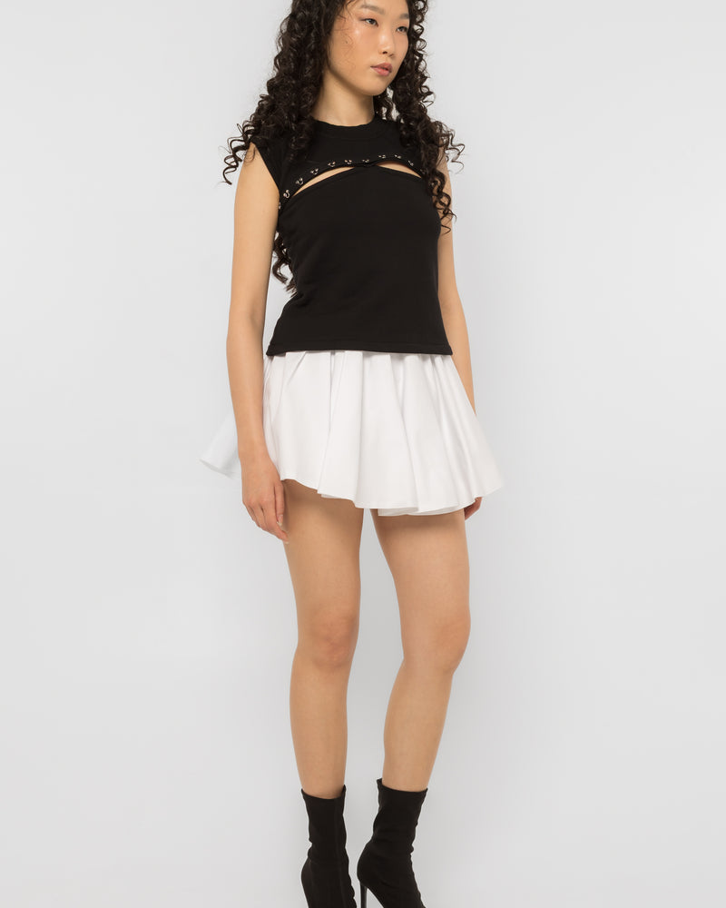 Full length black sleeveless top with steel ring chest cutout worn with a white skirt