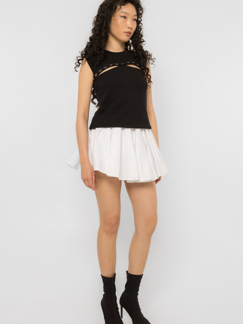 Full length black sleeveless top with steel ring chest cutout worn with a white skirt