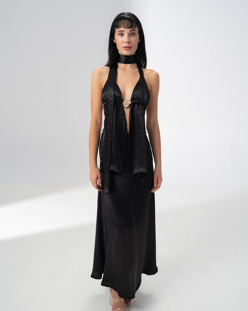 Model wearing the Girl Code black satin halter top and maxi skirt set with a deep V neckline