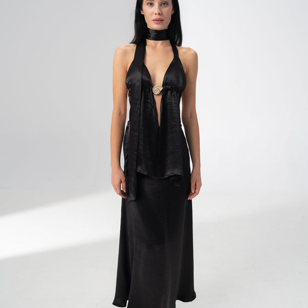 Model wearing the Girl Code black satin halter top and maxi skirt set with a deep V neckline