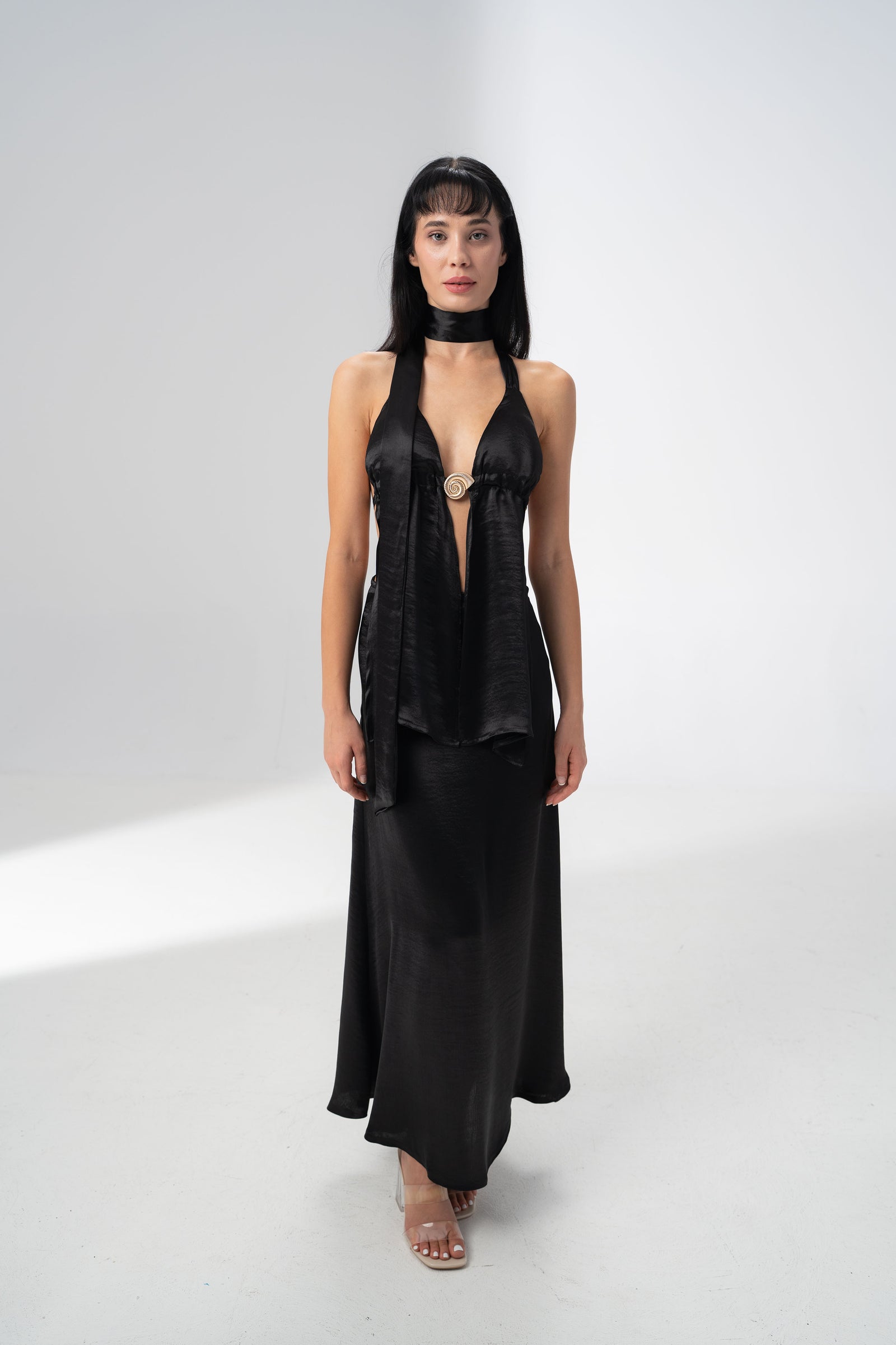 Model wearing the Girl Code black satin halter top and maxi skirt set with a deep V neckline