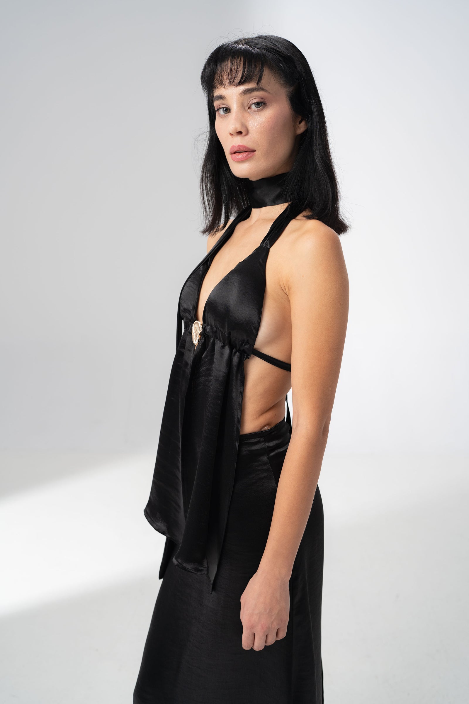 Open back of the black satin halter top tied with a long ribbon down the spine