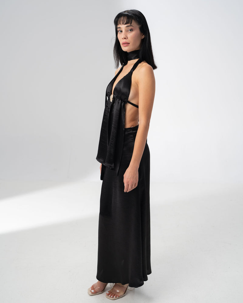 Deep V neckline of the black satin halter top gathered by a statement metal ring