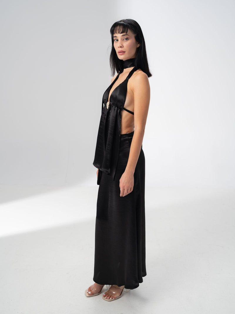 Deep V neckline of the black satin halter top gathered by a statement metal ring