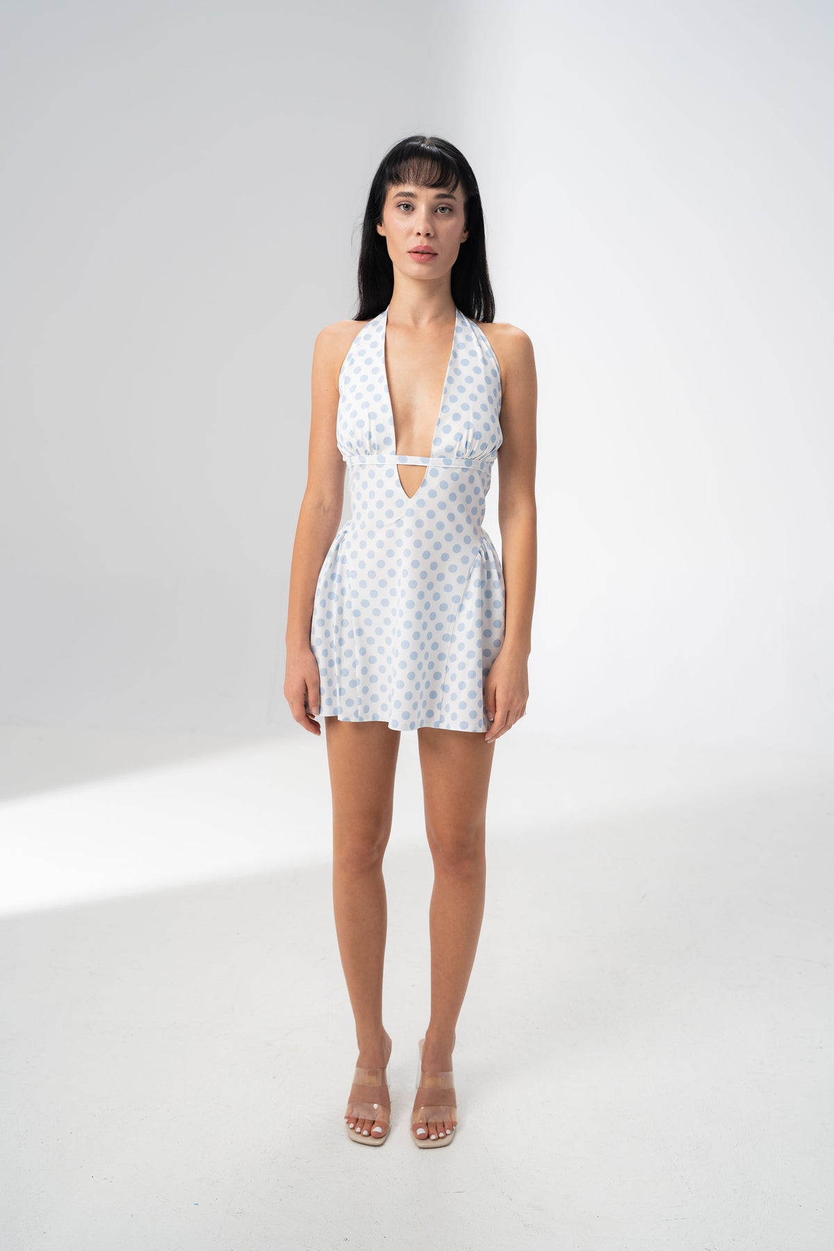 Model wearing the Girl Code blue polka dot halter dress with a deep plunging V neckline