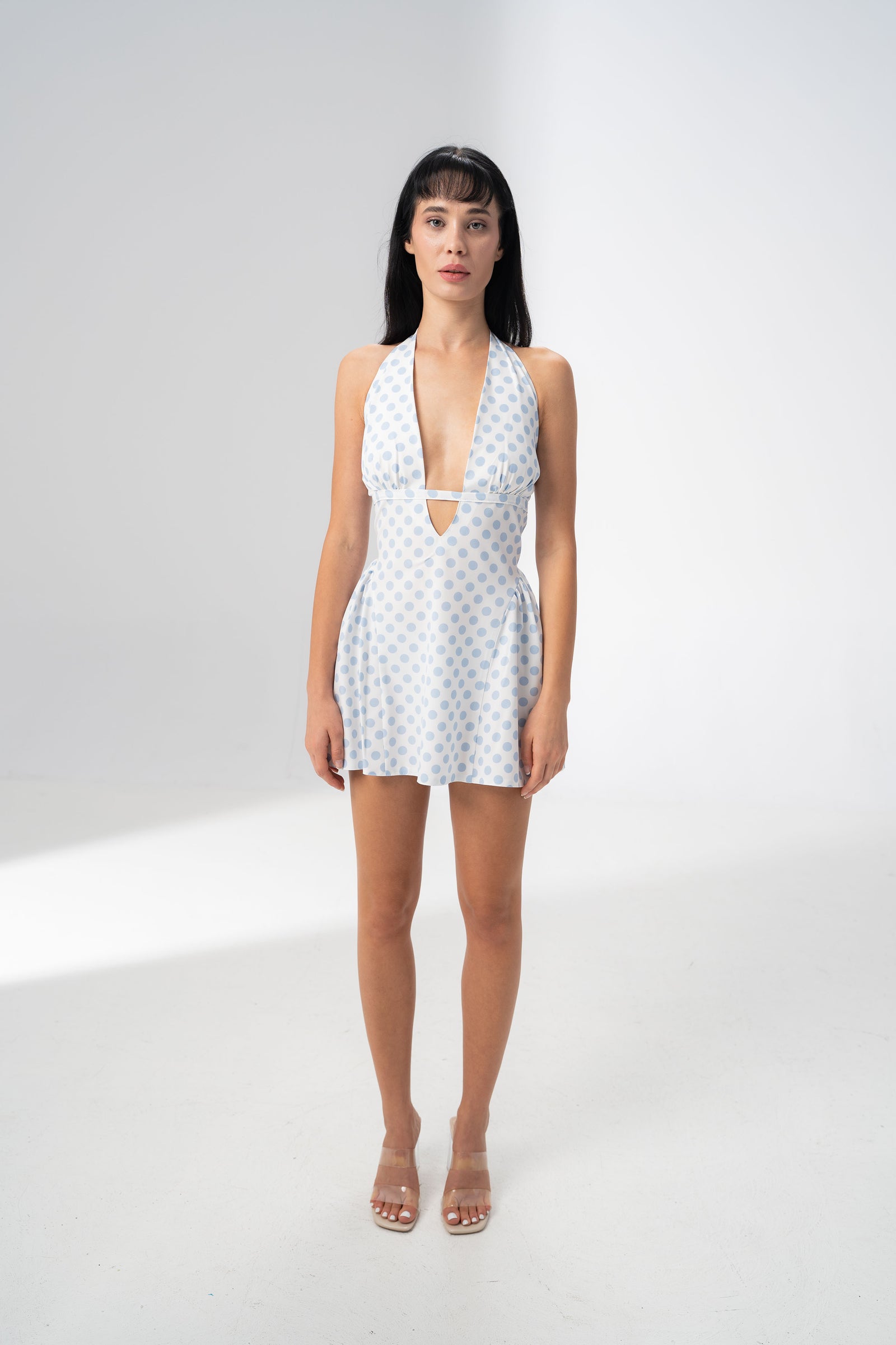 Model wearing the Girl Code blue polka dot halter dress with a deep plunging V neckline