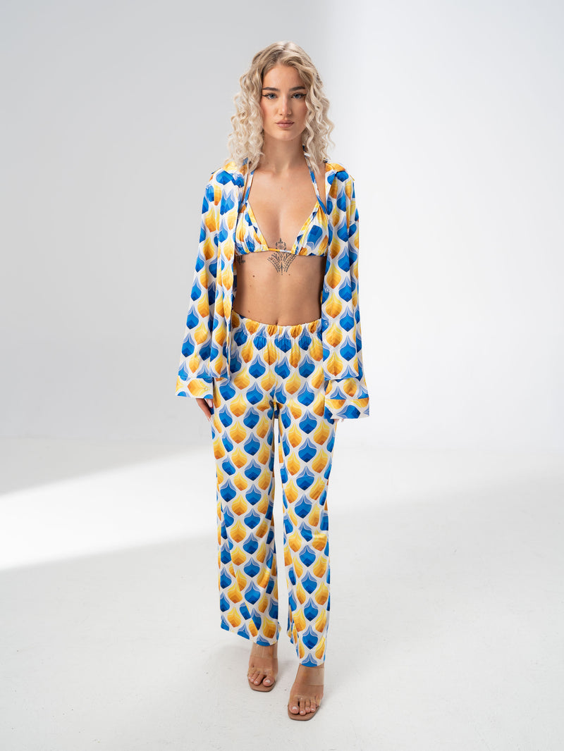 Model wearing the Girl Code blue and yellow satin three piece set with bralette, wide leg trousers and open shirt