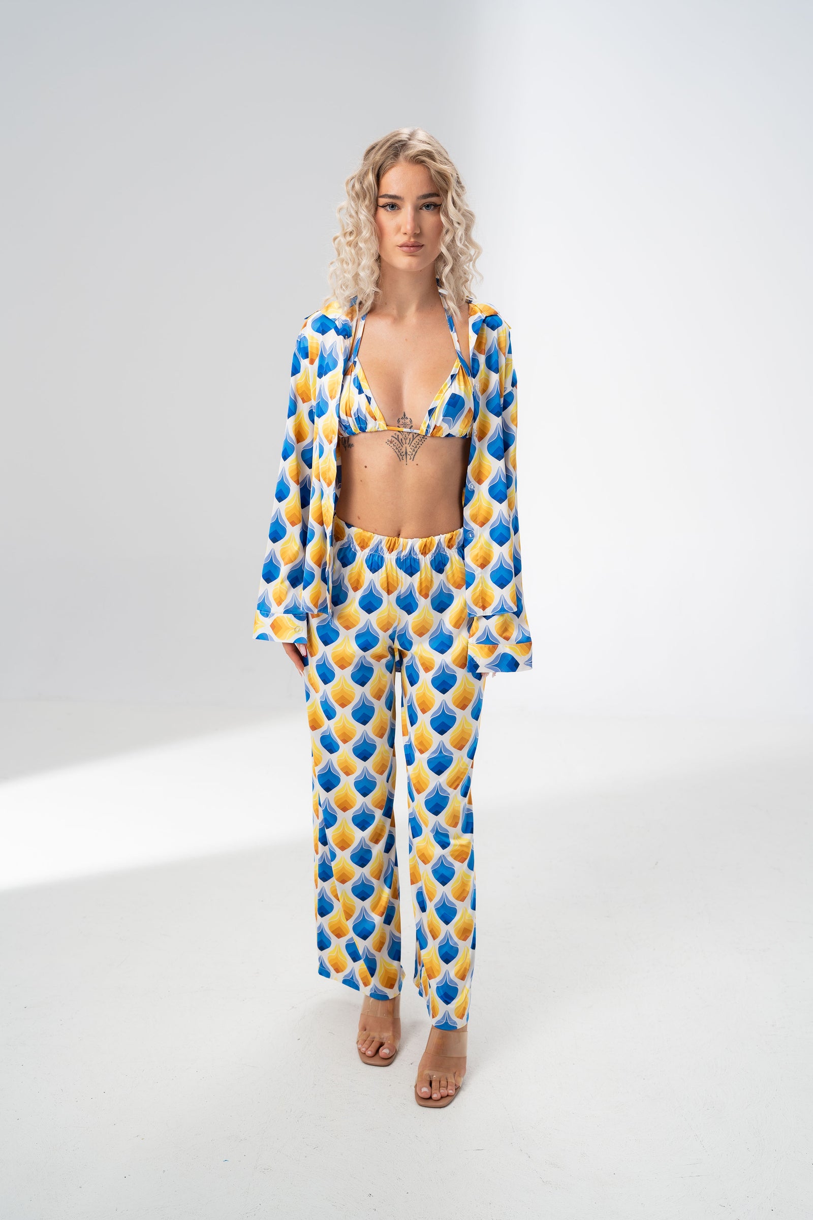Model wearing the Girl Code blue and yellow satin three piece set with bralette, wide leg trousers and open shirt