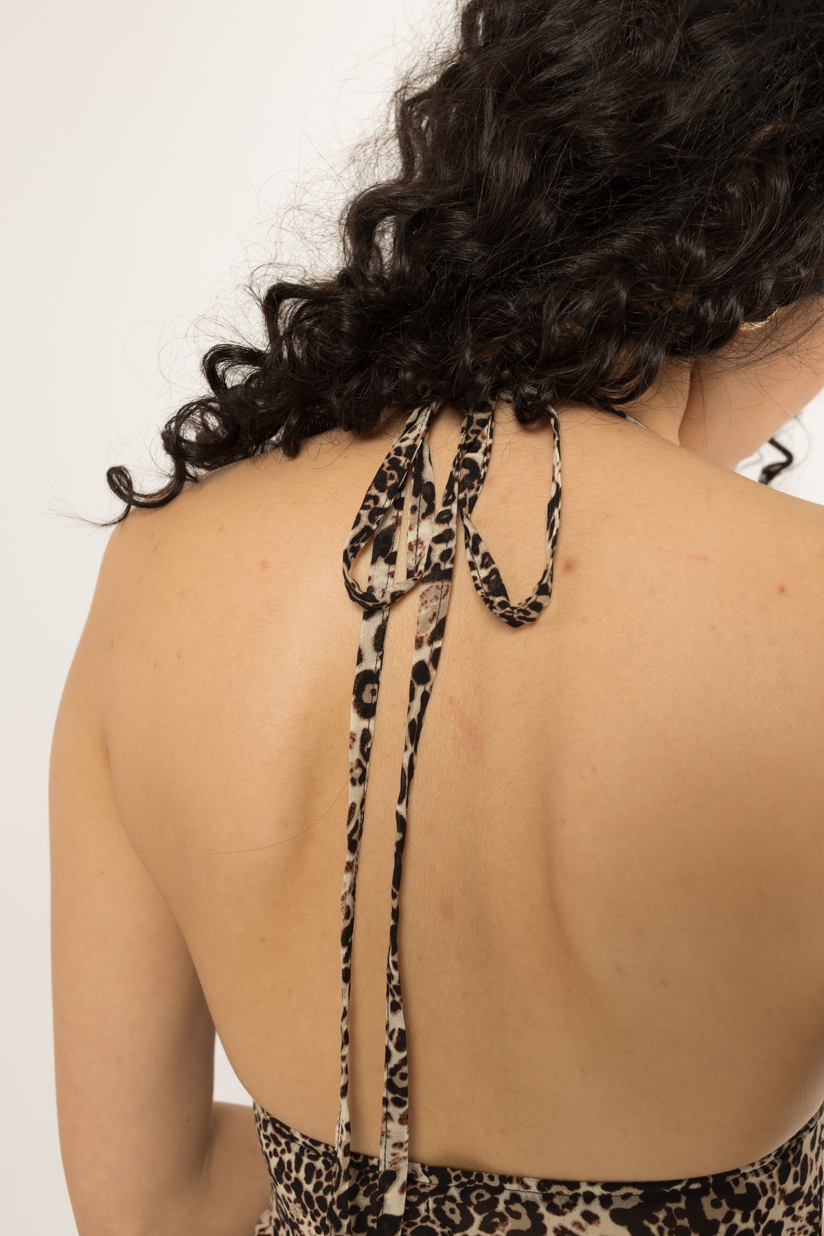 Self fabric halter ties knotted at the back neck of the leopard print long shirt