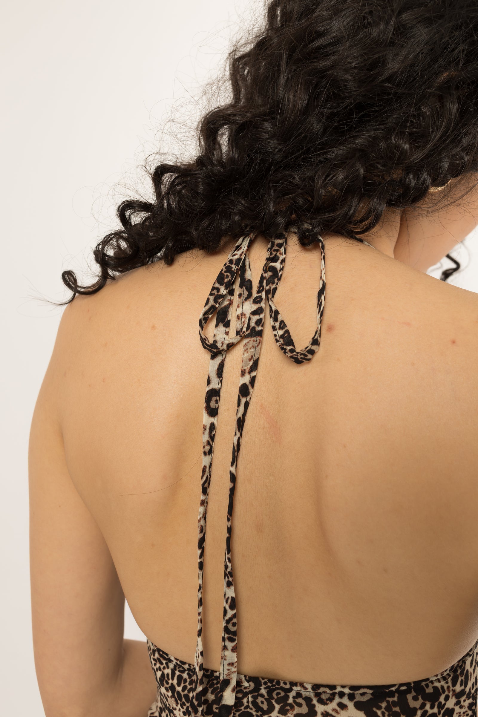 Self fabric halter ties knotted at the back neck of the leopard print long shirt