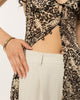 Button front of the leopard print long shirt left open at the waist over cream trousers