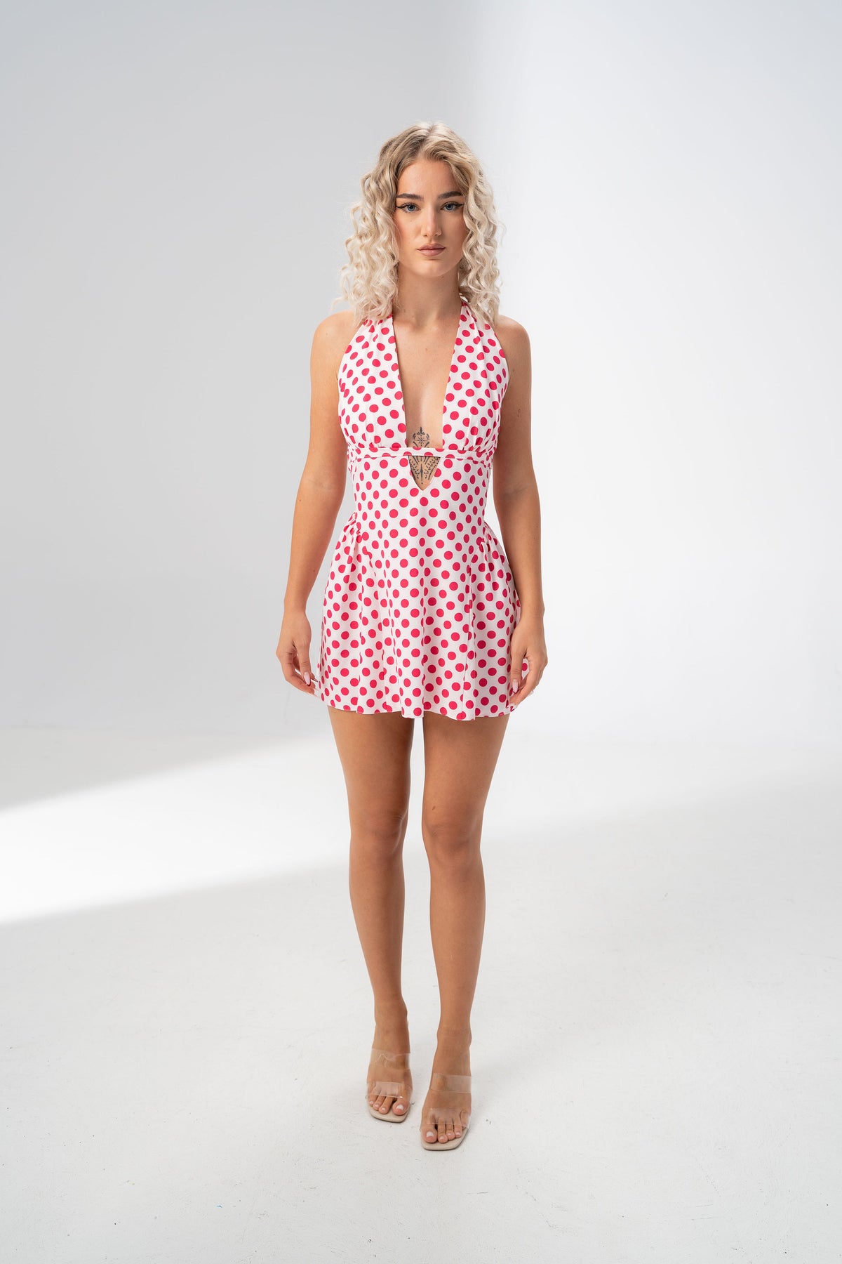 Model wearing the Girl Code polka dot halter mini dress with a deep plunging V neckline