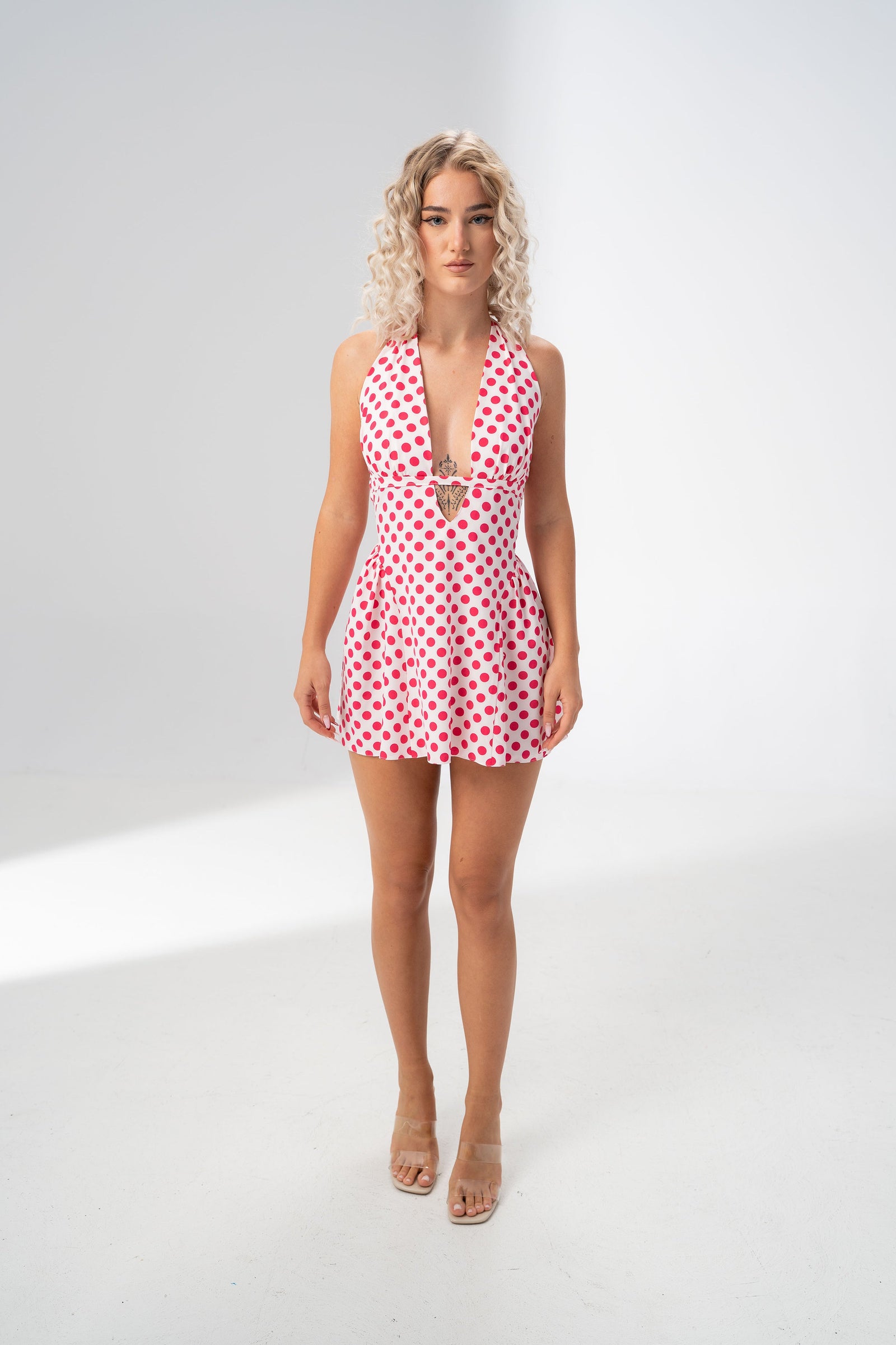 Model wearing the Girl Code polka dot halter mini dress with a deep plunging V neckline
