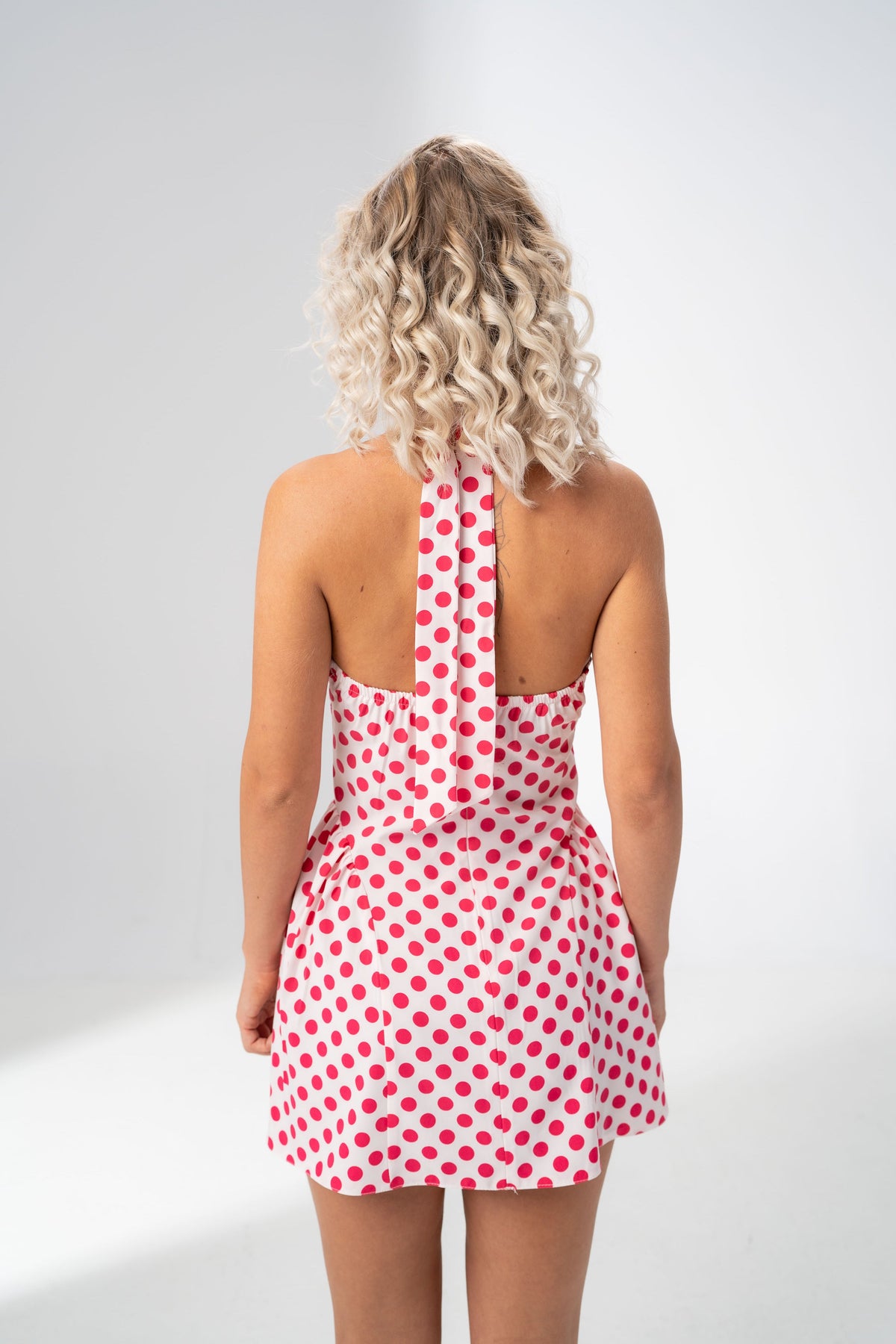Open back and halter tie detail of the Girl Code polka dot halter mini dress