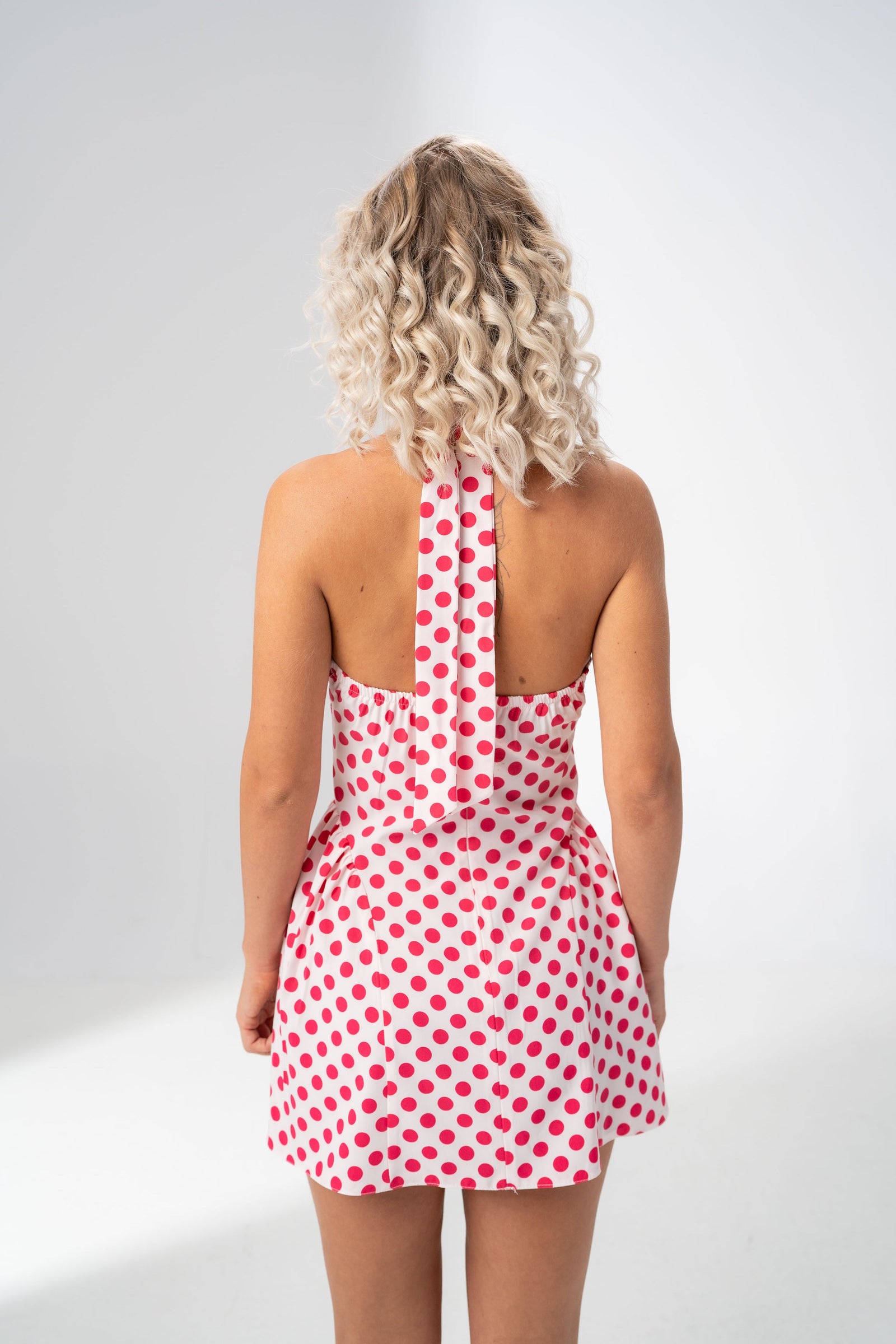 Open back and halter tie detail of the Girl Code polka dot halter mini dress