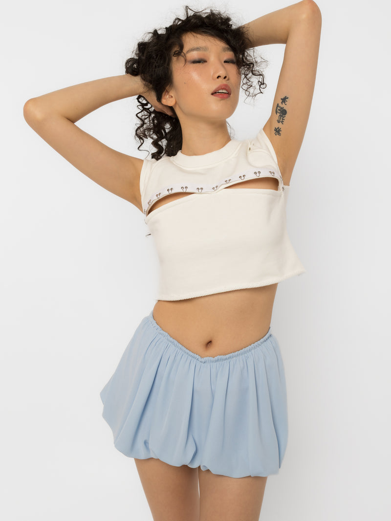 Model wearing Girl Code white pierced cutout crop top with steel rings