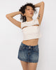 Model wearing Girl Code white pierced cutout crop top with steel rings, three quarter view