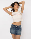 Model wearing Girl Code white pierced cutout crop top with steel rings, three quarter view